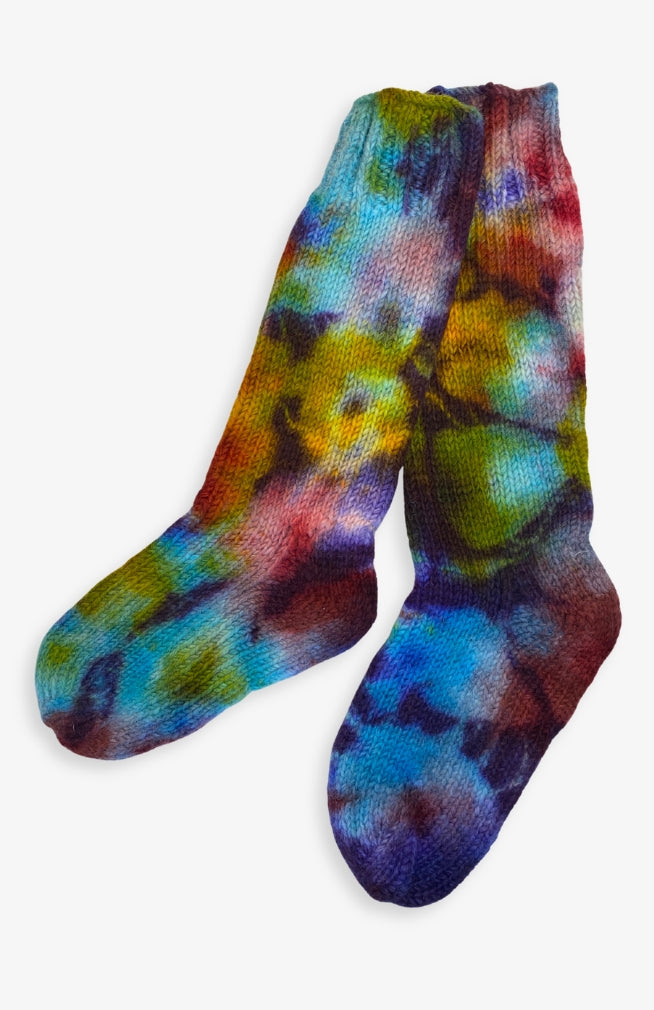 A pair of hand-knit socks featuring a vibrant tie-dye pattern with blue, purple, green, yellow, and red tones. Handmade by artisans in Nepal.