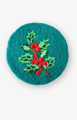 needle felted holly trivet on forest green background