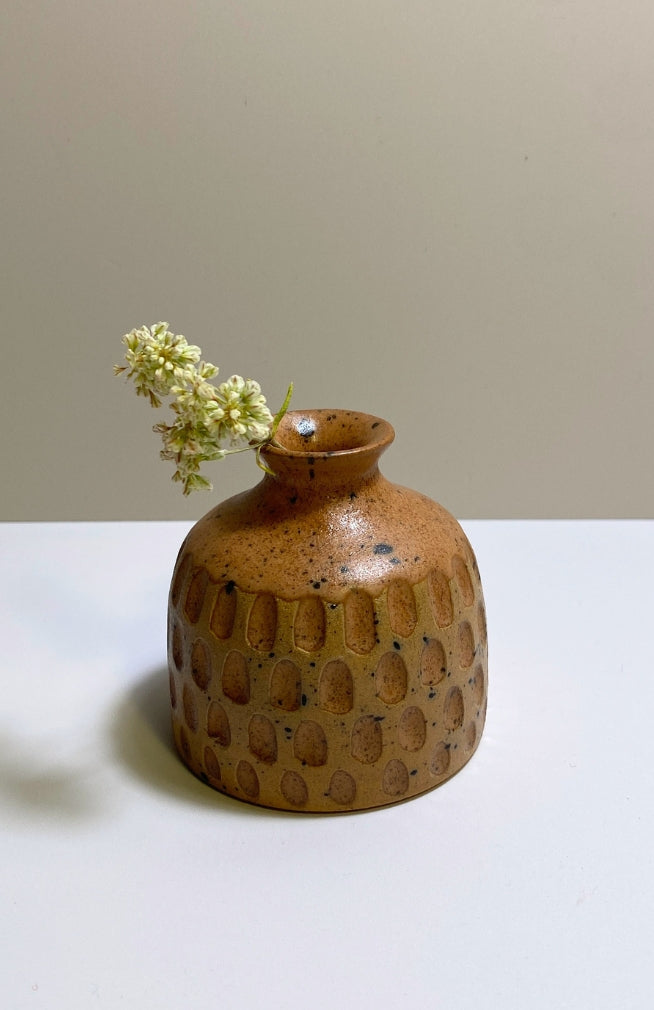 A small round ceramic bud vase with a textured surface and speckled brown and tan glaze, handmade in Nepal.
