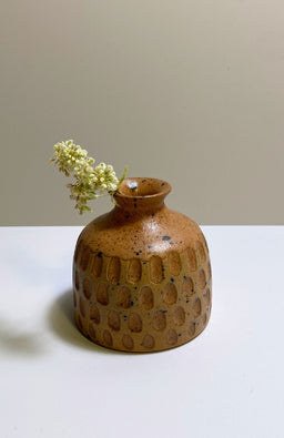 A small round ceramic bud vase with a textured surface and speckled brown and tan glaze, handmade in Nepal.