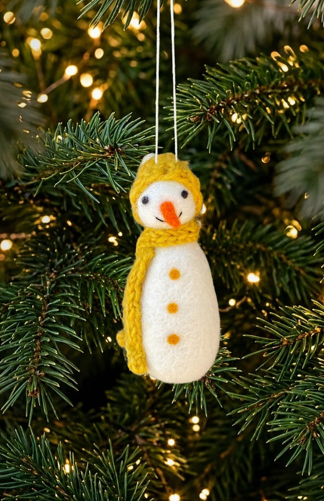 A handmade felt snowman ornament with a yellow hat and scarf and orange carrot nose. Handmade in Nepal.