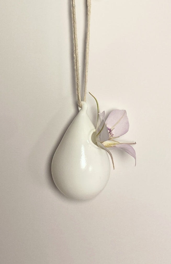 A white handblown glass hanging bud vase in tear drop shape with loop for hanging. Fair trade and handmade in Nepal.