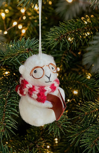 A white felted sheep ornament reading a book with round glasses and red-and-white patterned scarf.