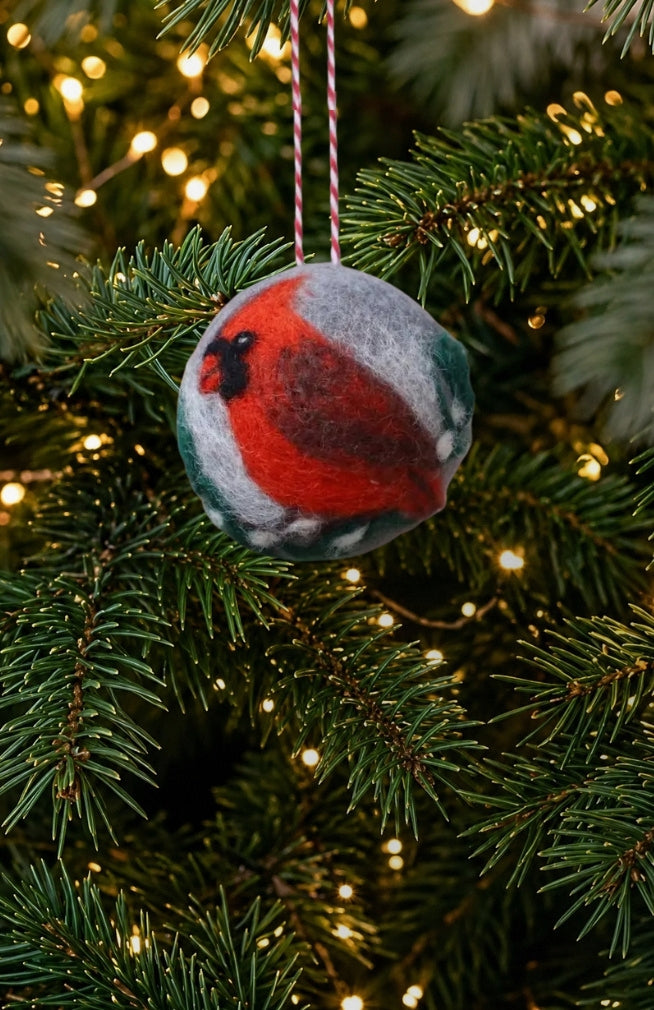 A round handfelted Christmas ornament with hand felted red cardinal bird design made of 100% New Zealand wool.