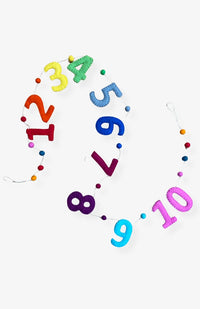 A handmade colorful number garland with colorful felt balls between numbers spelling out 1 -10 