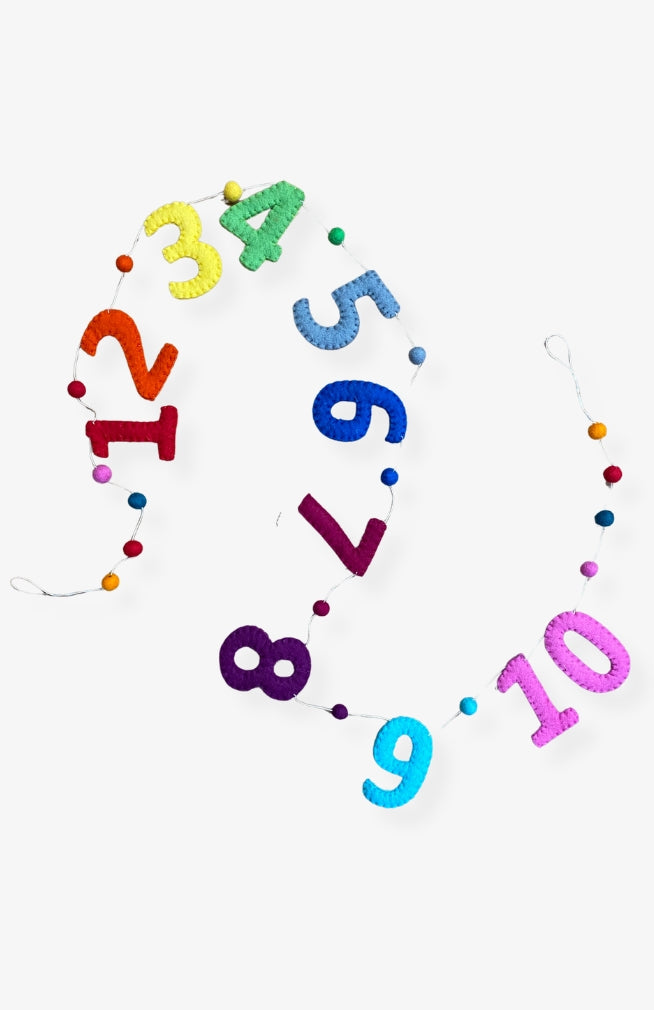 A handmade colorful number garland with colorful felt balls between numbers spelling out 1 -10 