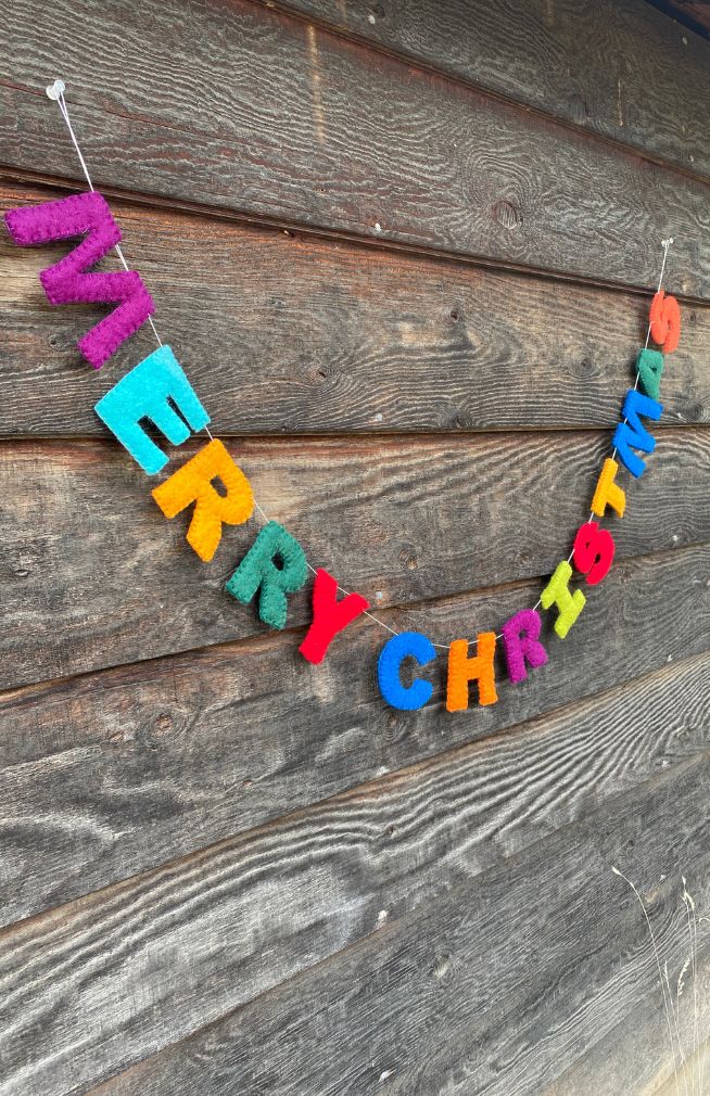 A colorful 'MERRY CHRISTMAS' letter garland made of felt, handmade in Nepal.