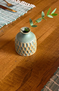 A small round ceramic bud vase with a textured surface and speckled brown and tan glaze, handmade in Nepal.