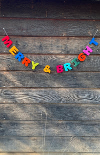 A colorful letter banner spelling 'MERRY & BRIGHT' on white string with loops for hanging