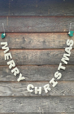 White felted "MERRY CHRISTMAS" garland with two overlapping green leaves at each end