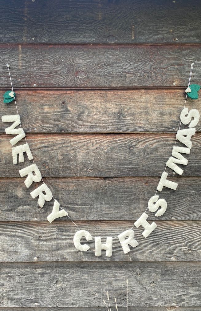 White felted "MERRY CHRISTMAS" garland with two overlapping green leaves at each end