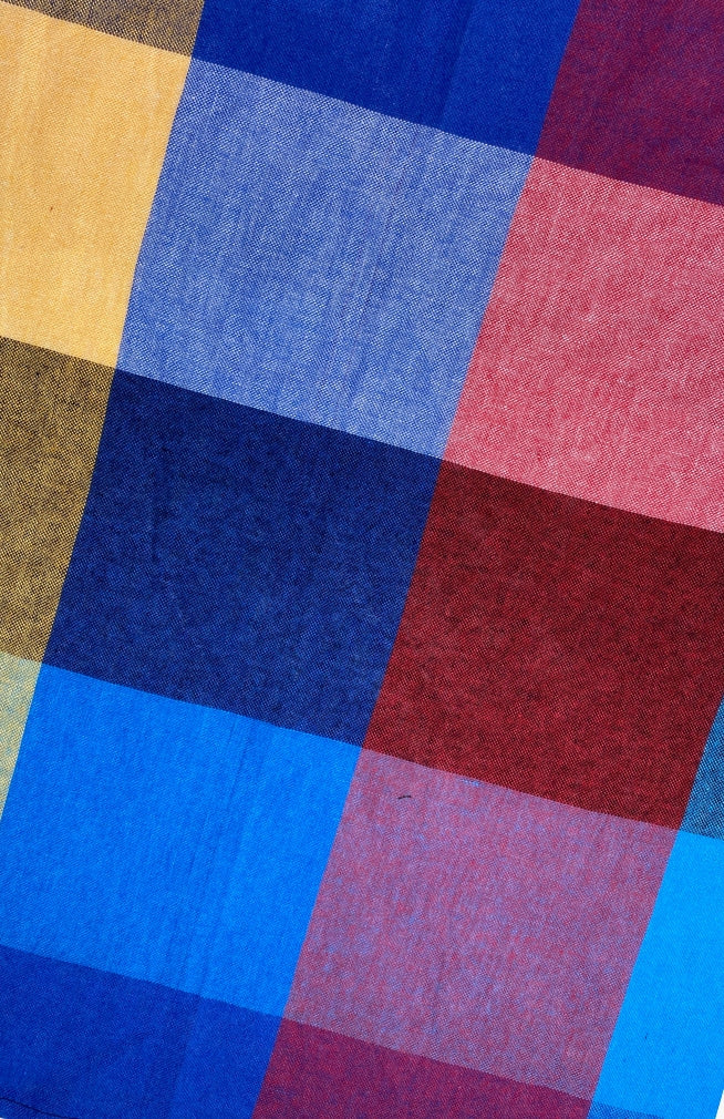 Close up image of red, blue, and yellow checked cloth napkin sold as a set of two, quick drying, handmade in Nepal. 