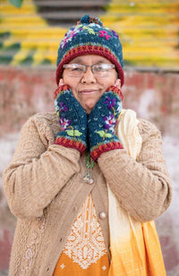Colorful hand knit wool hat with contrasting color roll cuff, top pom pom and flower embroidery