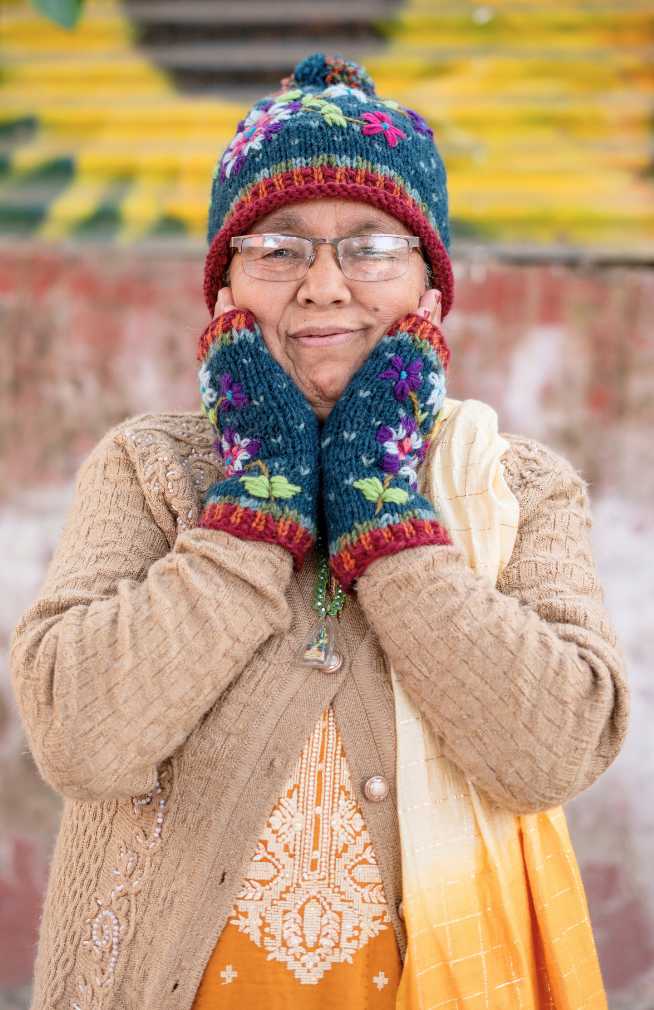 Colorful hand knit wool hat with contrasting color roll cuff, top pom pom and flower embroidery