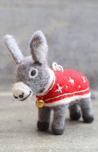 A hand felted wool donkey ornament wearing a red sweater with white stars and a gold bell.